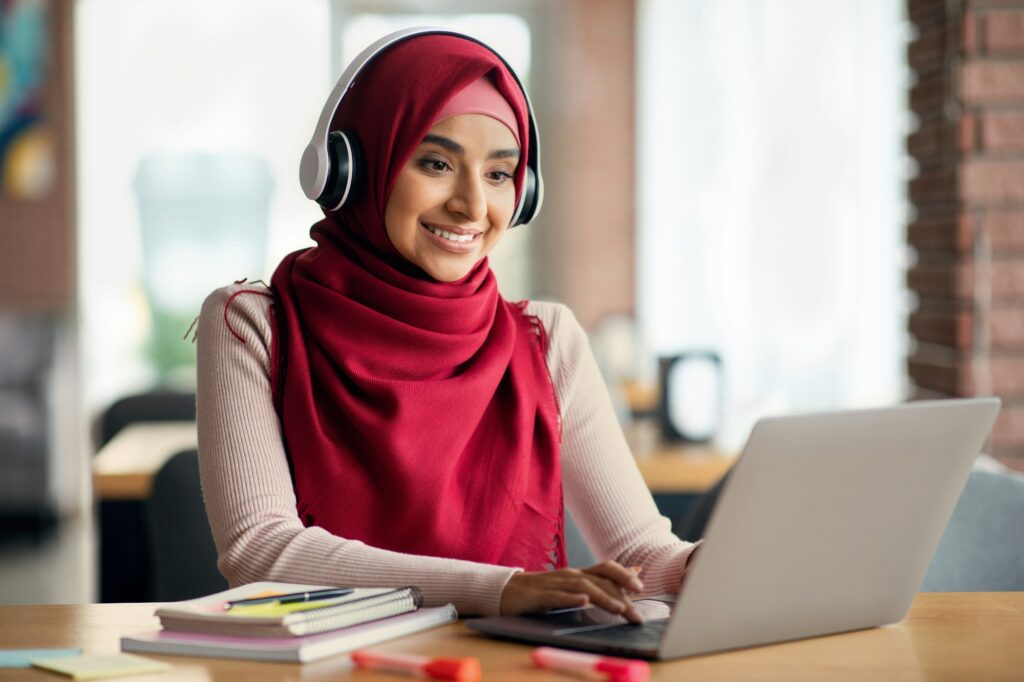 Joyful muslim woman attending online course, cafe interior, copy space